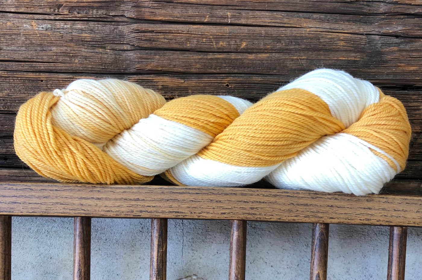 A naturally dyed skein of wool resting on a weathered log wall